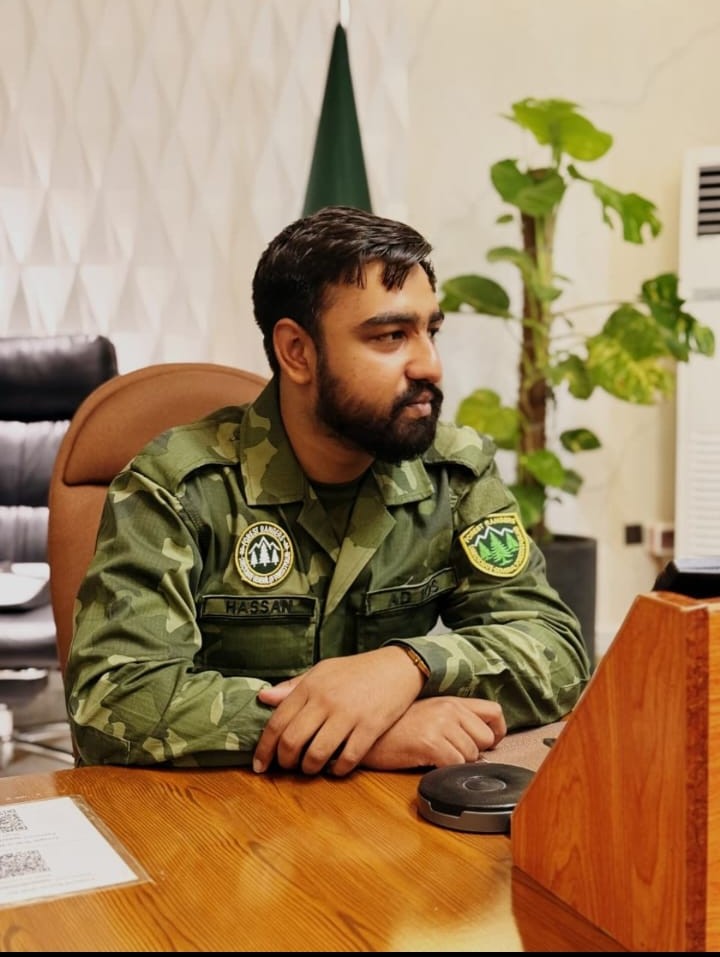 Hassan Iqbal seated at his desk in his Punjab Forest Department uniform